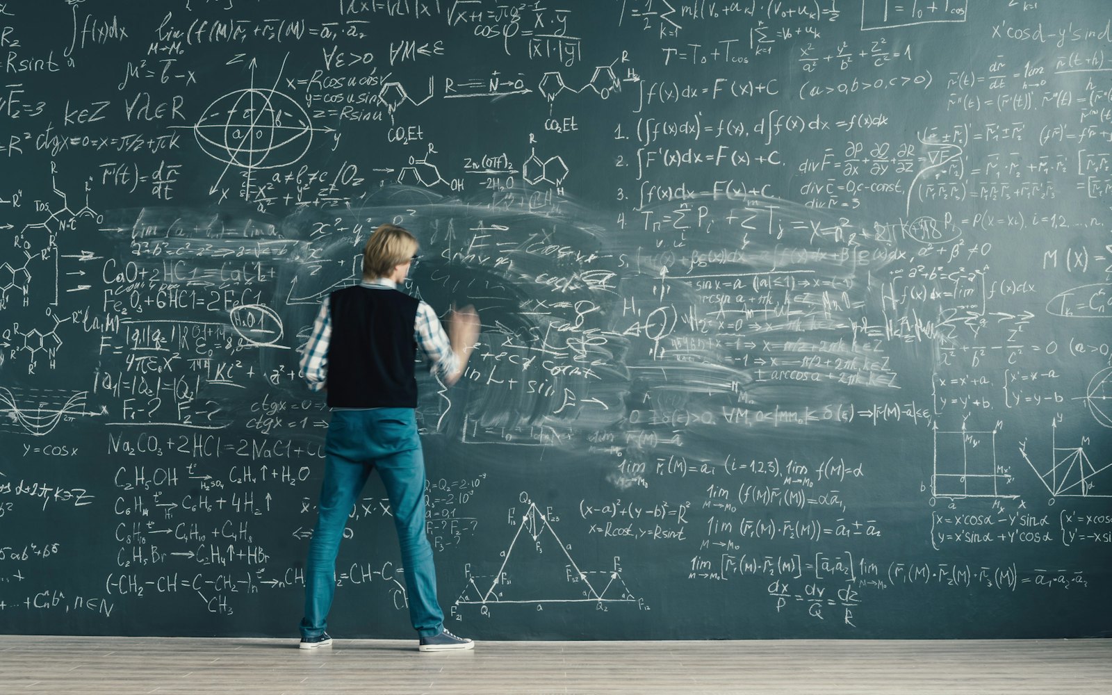 A person working through formulas on a chalkboard