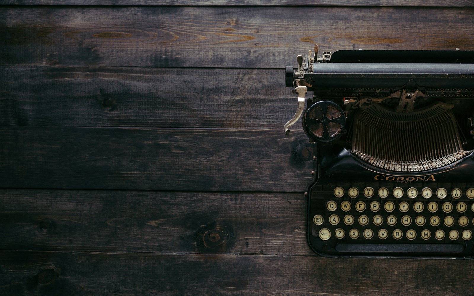 A black vintage typewriter on dark wooden planks